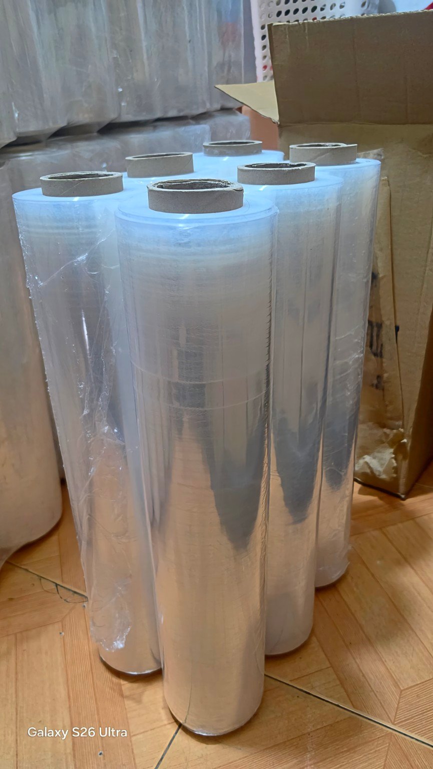 Upright clear stretch film rolls next to a shipping carton
